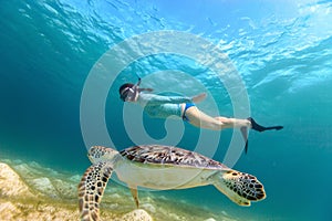 Young girl snorkeling with sea turtle