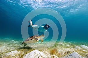 Young girl snorkeling with sea turtle