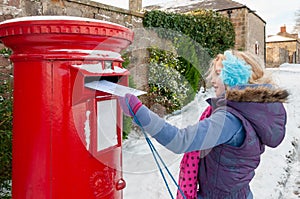 Young girl in a snow covered scene posting her letter to Santa