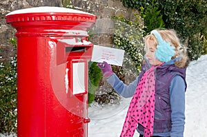 Young girl in a snow covered scene about to post her Christmas letter to Santa