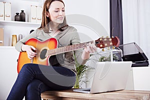 Young girl on sofa playing guitar