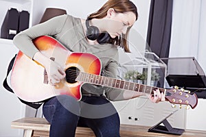 Young girl on sofa playing guitar