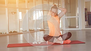 Young girl in sports clothes doing warm-up on the rug in the gym with tape