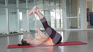 Young girl in sports clothes doing warm-up on the rug in the gym with tape