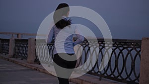 A young girl in sports clothes Jogging on the waterfront in the moonlight. the athlete is engaged in sports on the