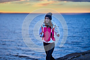 A young girl in a sports hat and jacket makes a morning jog on the embankment in the morning before the dawn of the sun.