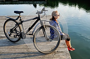 Young athletic woman in sportswear sits next to a bicycle