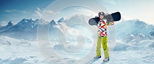 Young girl in sportswear standing with snowboard over snowy mountains background. Winter vacation