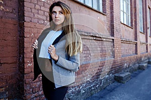 Young girl in a sportwear is exercising in front of the urban red brick wall. Phot was made on a sunny morning.