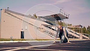 Young girl, sporty physique, at the stadium. She goes to start line, gets into a low start, and starts sprinting.