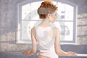 Young girl standing by bar showing her back