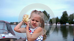 Young girl standing at beach holding shell up to ear