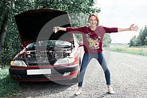 Young girl standing at the broken car and looking for help