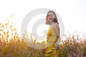 Young girl standing at brown field grass at sunset time