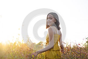 Young girl standing at brown field grass at sunset time