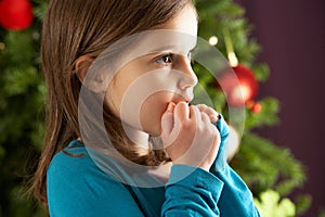 Young Girl Standing In Front Of Christmas Tree