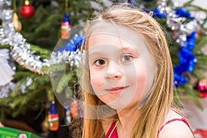 Young girl standing in front of christmas tree