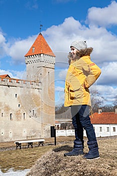 Young girl standing on hill agaist tower of the Kuressaare Episcopal Castle. The Kuressaare ciy, Saaremaa island, Estonia