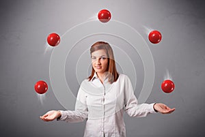 Young girl standing and juggling with red balls