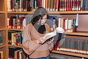 Young girl standing in library near bookshelves