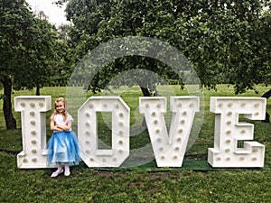Young girl standing at love neon letters in a park
