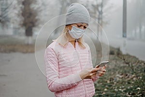 A young girl is standing near the road in a medical mask. Protection against a virus epidemic in a city