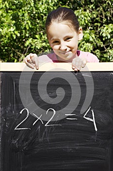 Young girl standing next to black slate photo