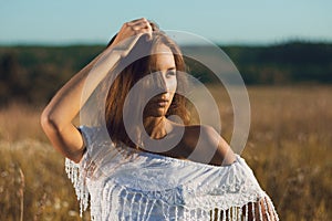 young girl standing posing in field of tall grass on sunset