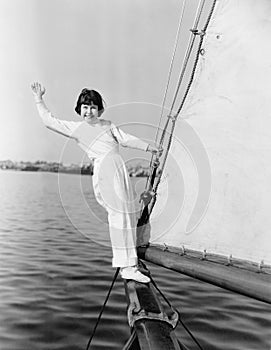 Young girl standing on a sailboat and waving