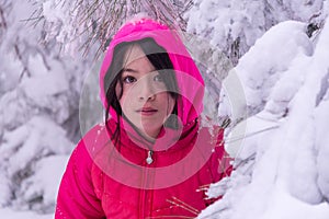 Young girl standing in snow covered trees