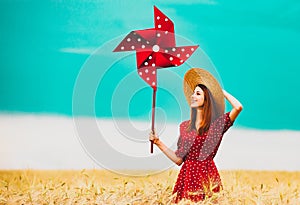 Girl is standing on a wheat field with pinwheel