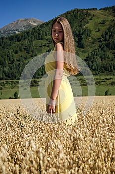 Young girl stands in a field with oats