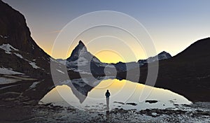 Young girl stands in front of the lake where the Matterhorn 4478m and Dente Blanche 4357m reflected in the Riffelsee