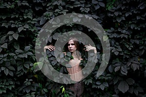 Young girl stands in green leaves alone with nature, a woman touches plants and dreams, a concept of a man in nature