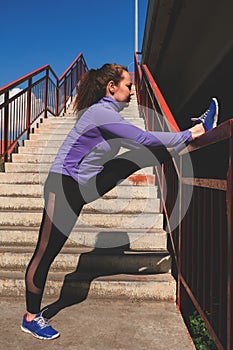 Young  girl stands with her foot on the railing of the stairs, workout urban sport concept