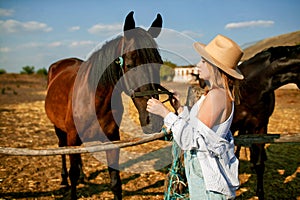 A young girl stands near a herd of horses in a farm.