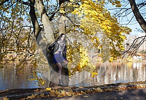 young girl stands near river in city park on autumn day