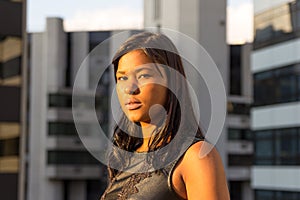 Young girl stands in profile and looks at camera. She is serious