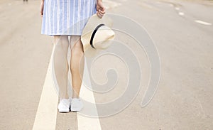 a young girl stands on the road at the dividing strip in a pink hat and white sneakers, sunset soldier