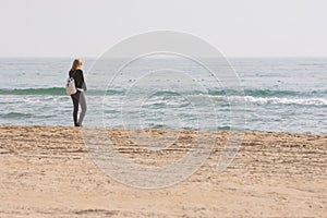 A young girl stands on seashore and looks at the sea