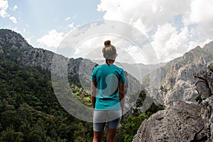 Young girl stands on top of the mountain