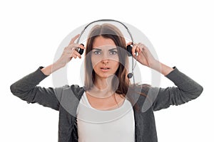 A young girl stands up straight into the camera and looks keeps earphones hands