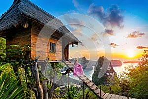 Young girl on steps of house on tree at sunrise in Nusa Penida island, Bali in Indonesia