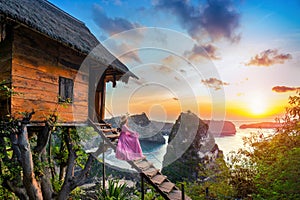 Young girl on steps of house on tree at sunrise in Nusa Penida island, Bali in Indonesia