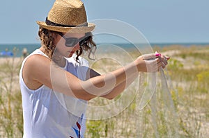 Young girl in a straw hat, sand in hands