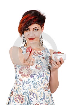 Young girl stretches strawberries in camera.