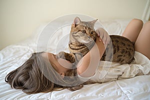 Young girl stroking cat lying on bed