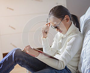 Young girl studying, reading books and writing. Female student reading book at home