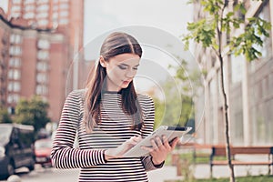 Young girl is studying in the spring park outside, browsing on h