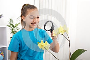 Young girl studys the structure of an orchid flower with a magnifier photo